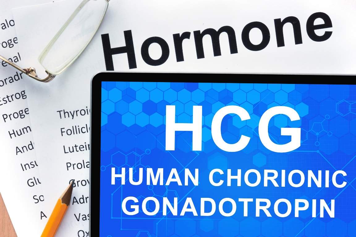Papers with hormones list and tablet with words Human chorionic gonadotropin (HCG). Medical concept.